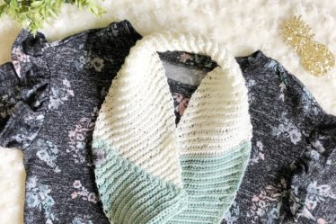 Cream and green crochet infinity scarf made with the Kelsi Scarf pattern flat lay with a floral blouse